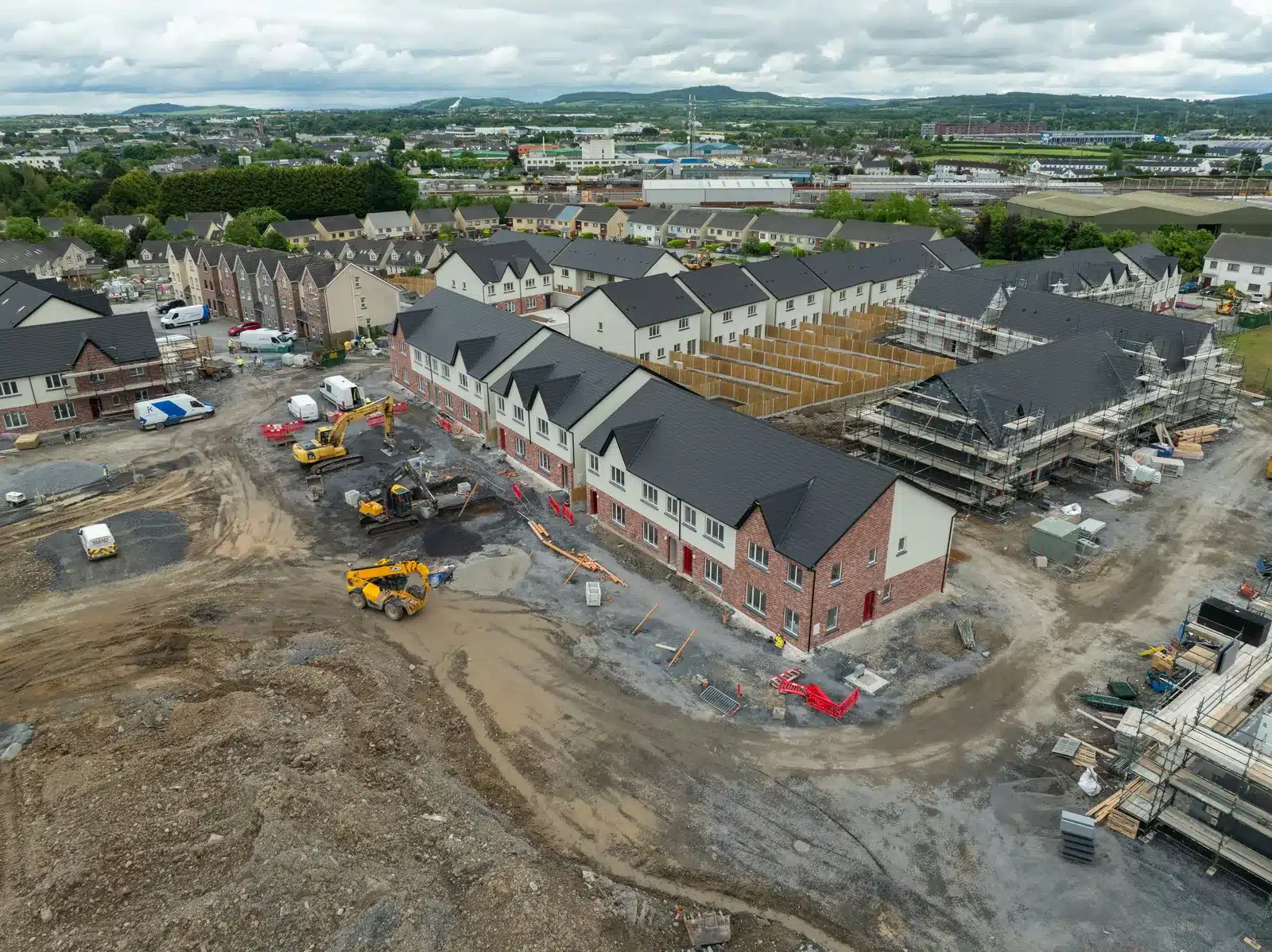 Drone Construction Monitoring 4 Drone view of a residential housing development mid-build, with completed terraces, active plots and site roads, Ireland